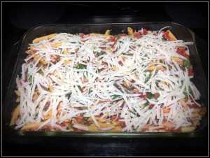 veggie chicken pasta in a glass casserole dish topped with mozzarella cheese